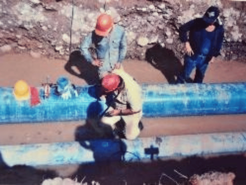 Operarios ensamblando tramos de tubería en la zanja de instalación