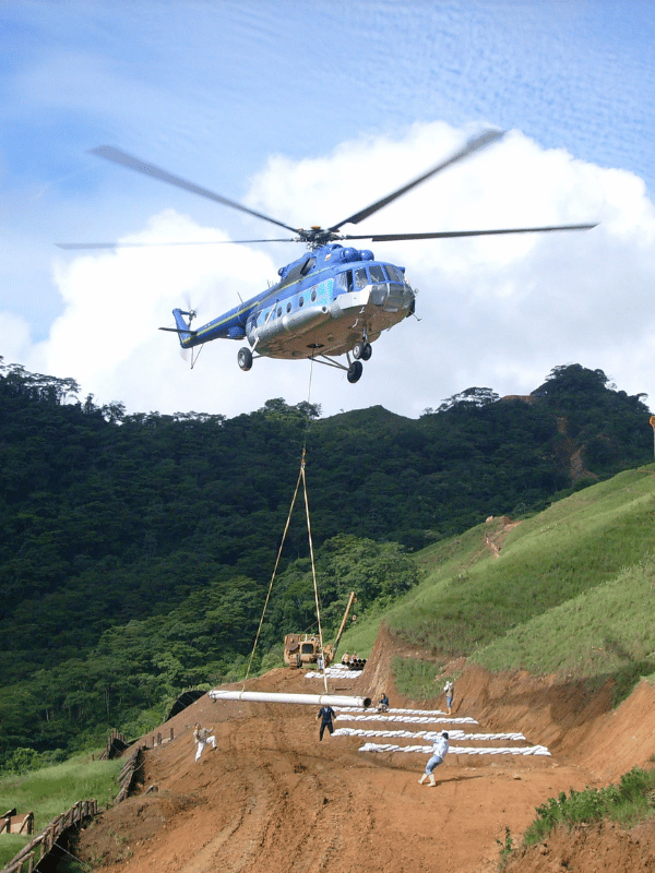 Helicóptero transportando tramos de tubería a un frente de obra en montaña