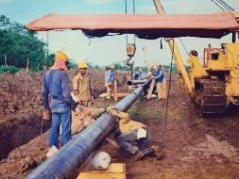 Cuadrilla descendiendo tubería a la zanja con apoyo de maquinaria