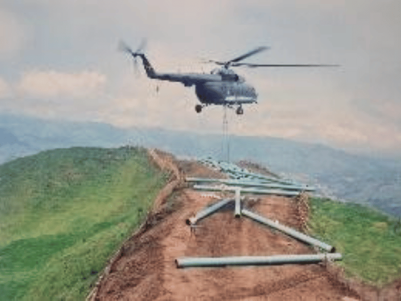 Helicóptero apoyando el tendido de tubería en zona montañosa