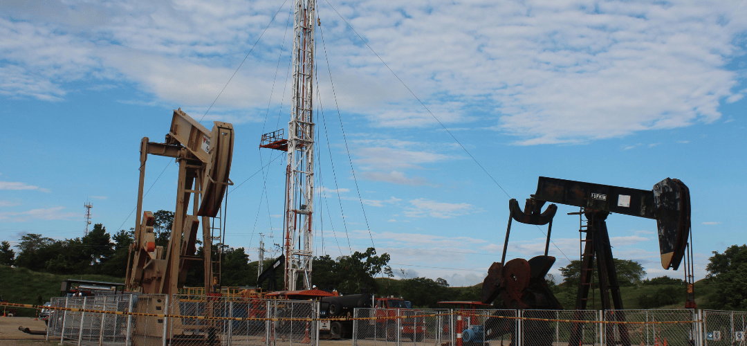 Balancines de bombeo y torre de perforación en un campo petrolero en producción